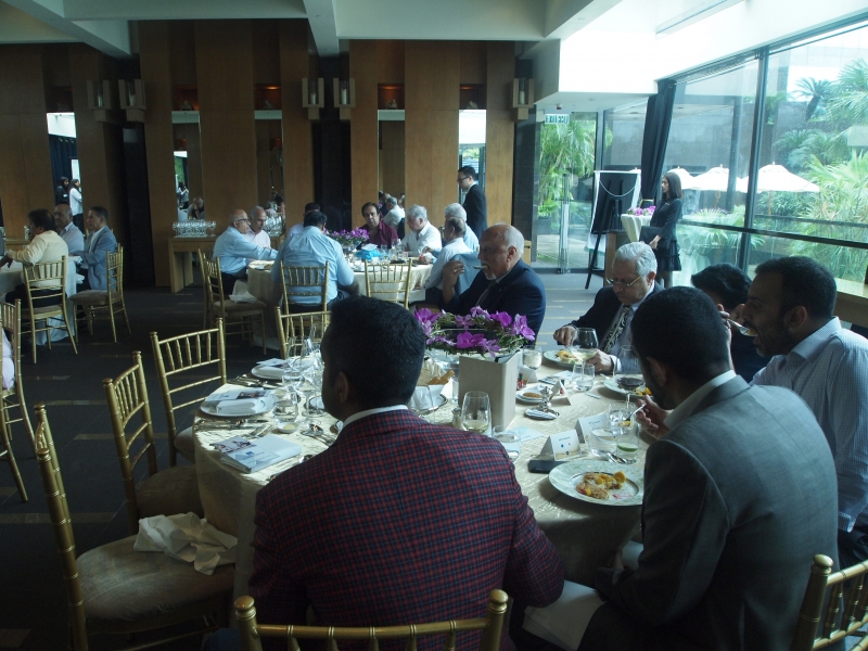 men seated at lunch turn to listen to woman presenting