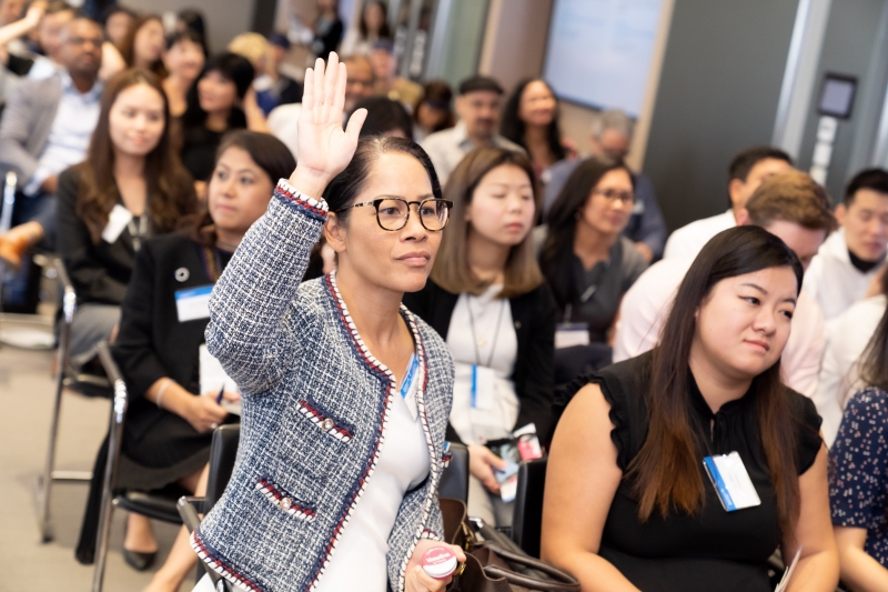 woman with glasses raises her hand for a question