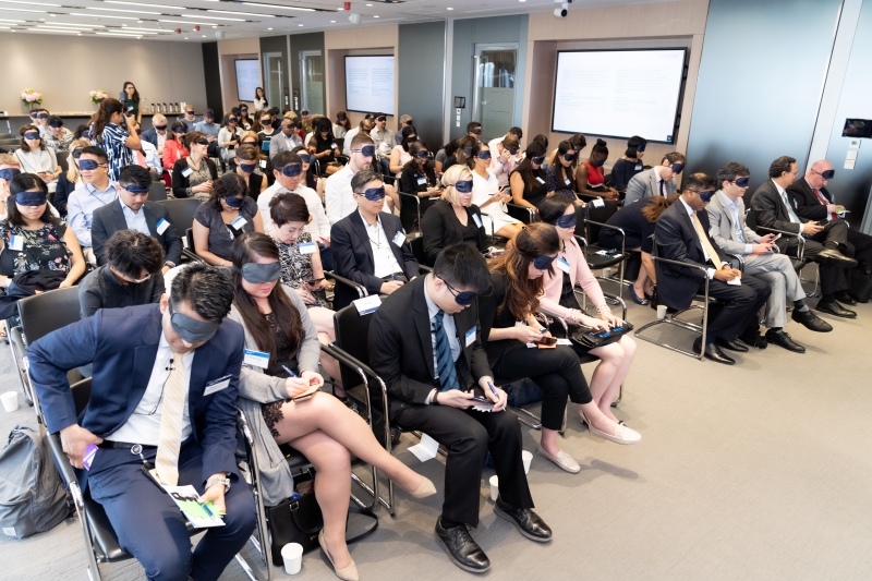 seated participants blindfold themselves with masks 