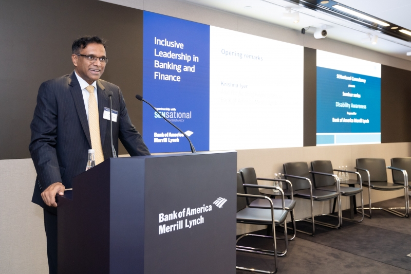 south asian man stands at podium announcing