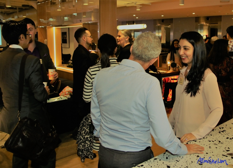 Many people in suits and office attire mingle and chat casually in a restaurant setting