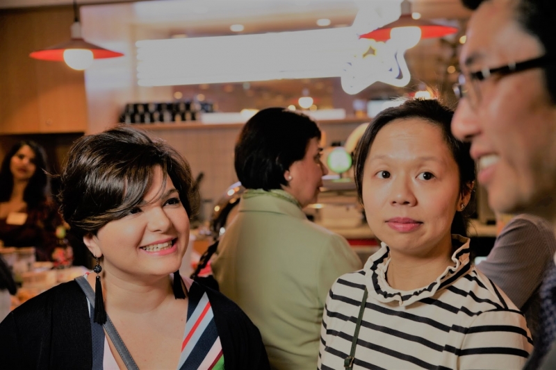 Two women listen curiously to a man with glasses