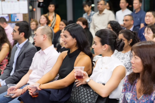 A photo of audience members in business attire, sitting in rows