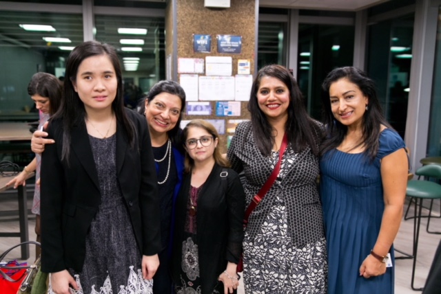 5 women in business attire are grouped together for a photo