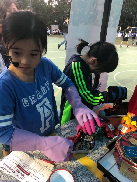 2 girls can be seen standing at a table and decorating shoes.