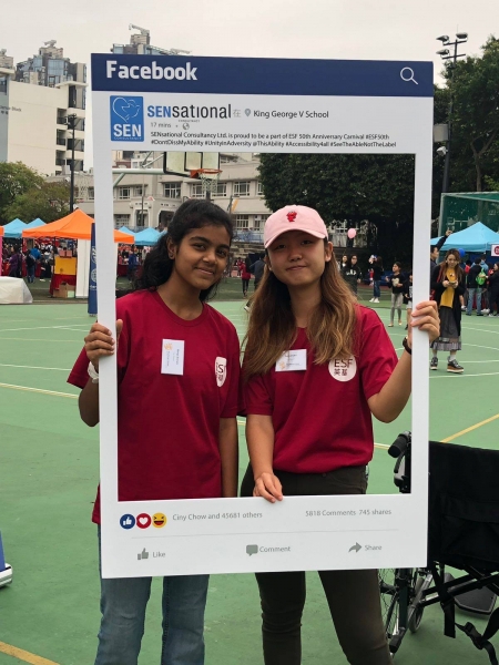 2 female ESF students can be seen posing behind the SENsational Facebook post photo frame