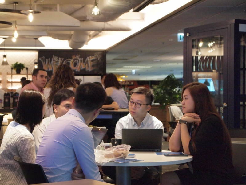 A group of men and women in business attire sitting at a table having a discussion.