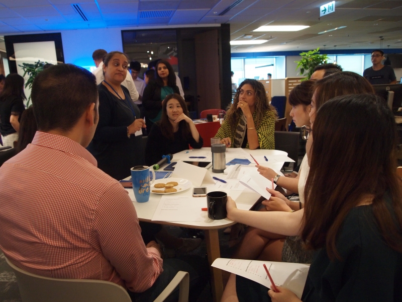 SENsational and Colliers staff in a group discussion, the Colliers staff are seated at tables while SENsational staff members move from table to table.