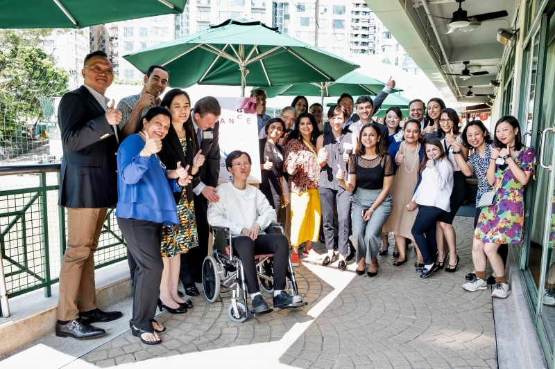 A group of men and women in business attire doing the thumbs-up sign