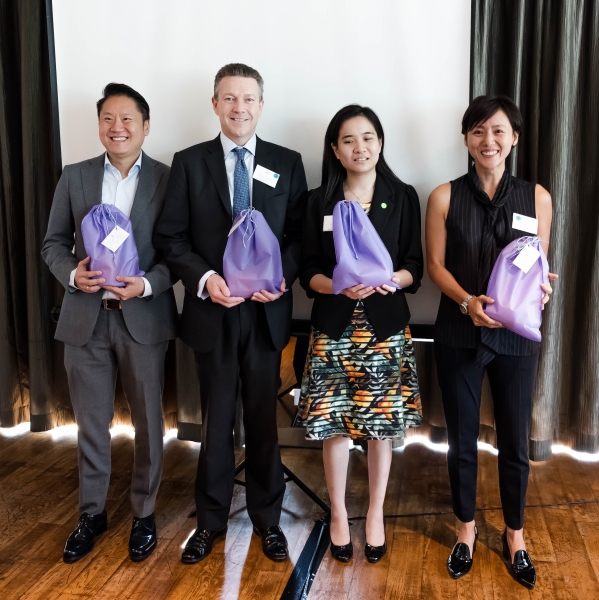 2 men and 2 women in business attire holding gift hampers
