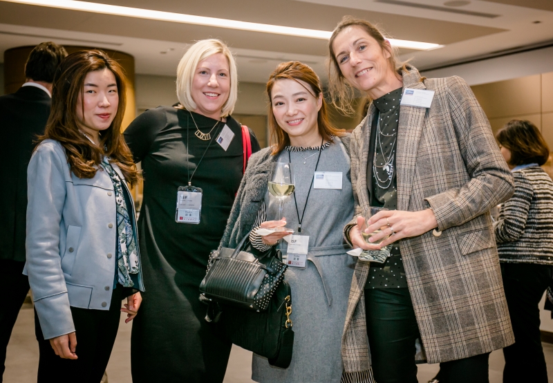 4 women in business attire are grouped together for a photo