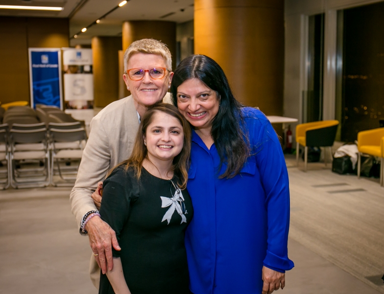 3 women in business attire are grouped together for a photo