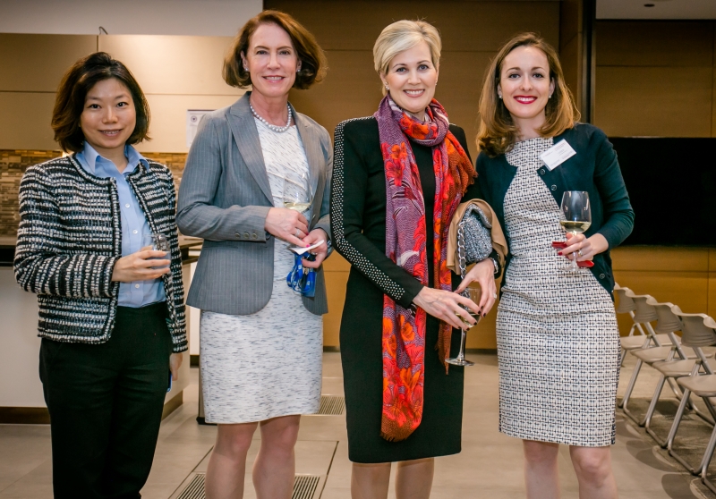 4 women in business attire are standing together for a photo