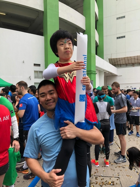a man holds a young boy up who is holding a sensational consultancy balloon