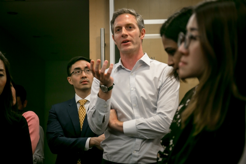 A man in business attire is asking a question to the off-picture panel members