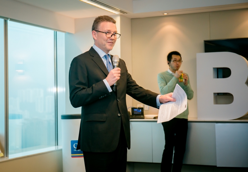 A man in a suit is giving a speech to the of-picture audience members