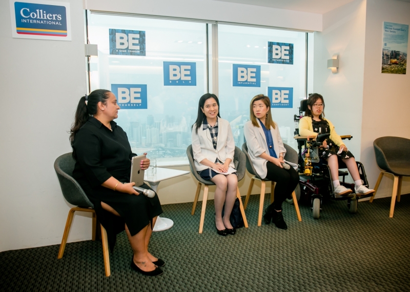 4 women in business attire who are part of the panel discussion are seated and having a conversation.