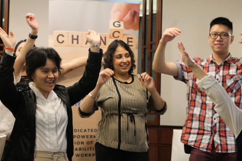 three individuals with disabilities cheering and raising their hands in the air