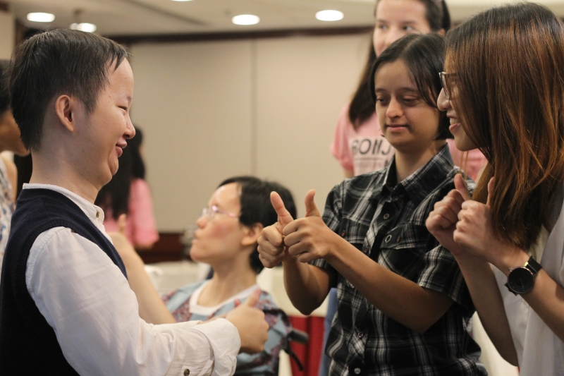one man and two women of differing abilities shake hands smiling