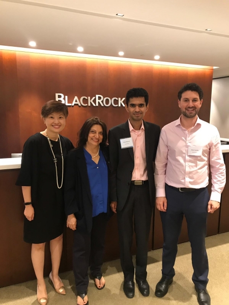 two men and two women stand in front of BlackRock backdrop smiling