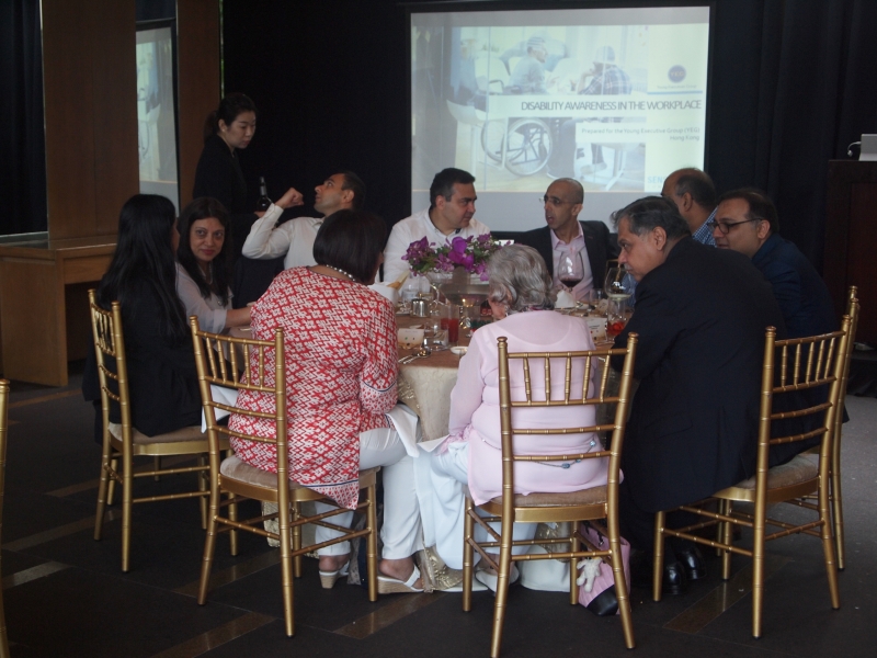 group of business suited people sit down around round lunch table